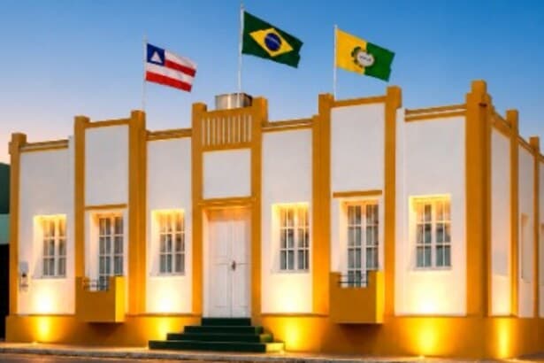 Fachada do Memorial de Irecê iluminada ao entardecer, com as bandeiras da Bahia, do Brasil e de Irecê